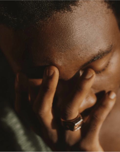 Person with hand covering face, expressing emotion, wearing a ring.